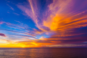 Naklejka na ściany i meble Stunning colorful sunset, blue sky, yellow purple cirrus clouds, orange sun, dark sea. Sunset on Jimbaran, South Kuta, Bali, Indonesia.