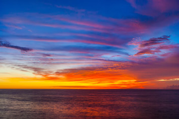 Naklejka na ściany i meble Stunning colorful sunset, blue sky, yellow purple cirrus clouds, orange sun, dark sea. Sunset on Jimbaran, South Kuta, Bali, Indonesia.
