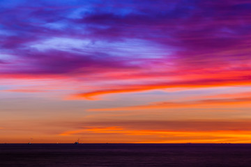 Stunning colorful sunset, blue sky, yellow purple cirrus clouds, orange sun, dark sea. Sunset on Jimbaran, South Kuta, Bali, Indonesia.