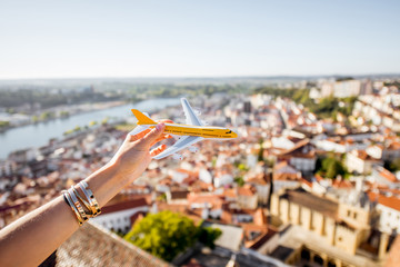Holding a toy airplane on the city background in Coimbra during the sunset in the central Portugal