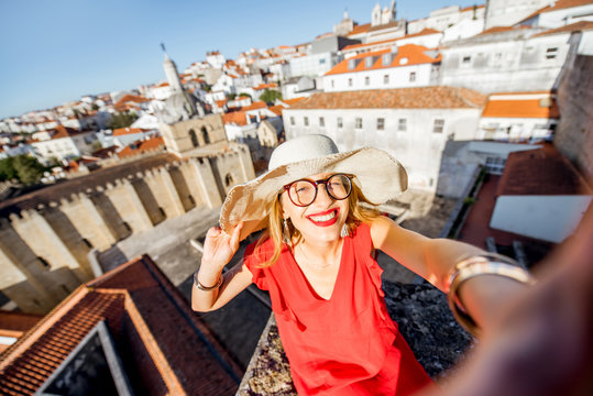 Portrait of a young woman tourist in red dress on the old city background traveling in Coimbra city in the central Portugal