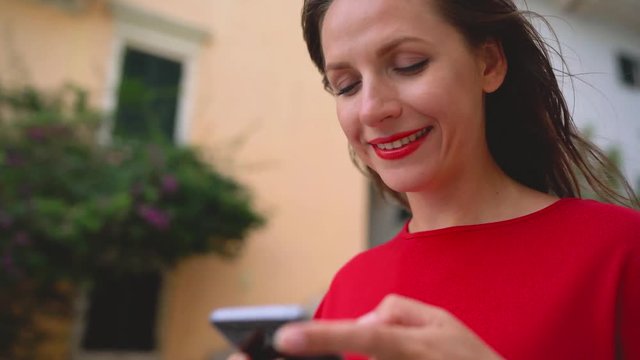 Happy woman talking on the smartphone while standing on the stairs outdoors