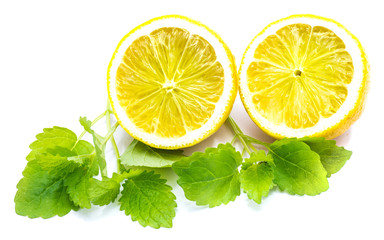 Two cross section lemon halves and fresh green lemon balm leaves isolated on white background .