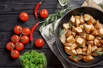Composition with delicious rosemary potatoes in pan on table