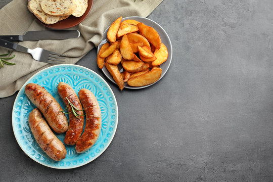 Plate with delicious grilled sausages on grey background