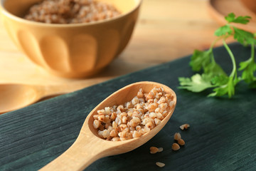 Wooden spoon with cooked buckwheat on table