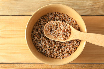 Bowl with cooked buckwheat on wooden background