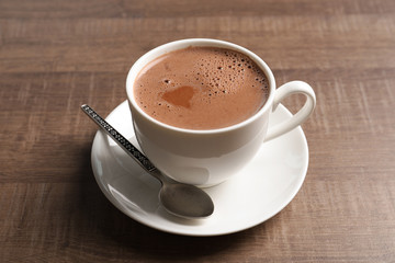 Cup with delicious cocoa drink on wooden background
