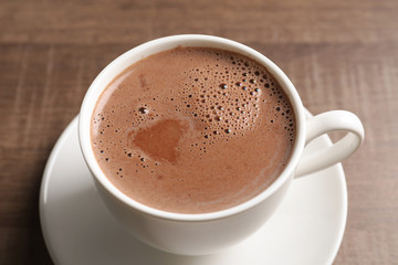 Cup with delicious cocoa drink on wooden background