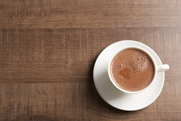 Cup with delicious cocoa drink on wooden background