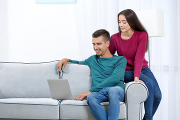 Young couple with laptop on sofa at home