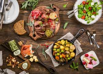 Flat lay of delicious dinner table with roasted meat steak, appetizers and desserts. Top view....