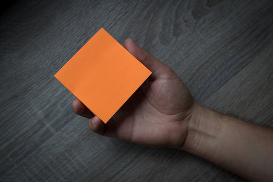 Hand holding an orange note paper - Business Concept