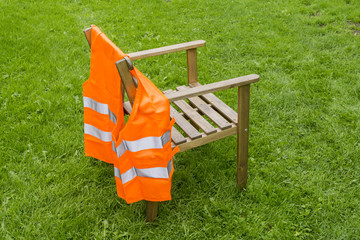 Chair with orange safety vest on a meadow
