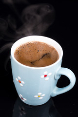 Cup of coffee isolated above black background with reflections