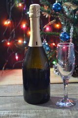 a bottle of champagne and glasses on the background of a Christmas tree decorated with balls and New Year's lights. happy christmas concept. Ribbon, baubles and wine against Christmas lights