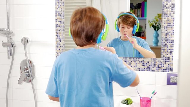 Happy kid dancing while washing teeth listening music doing dub gesture