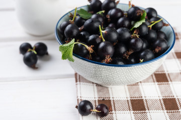 Fresh blackberries (black currant) in ceramic bowl on white wooden table, selective focus