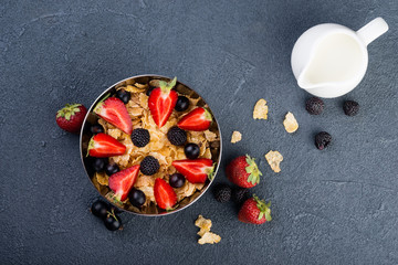 Cornflakes with berries on dark  background, fresh healthy  breakfast concept, flat lay