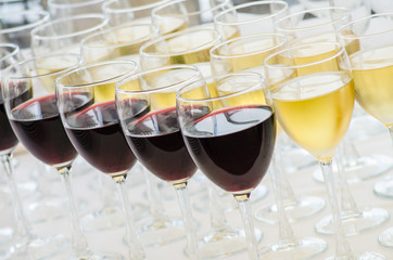 rows of wine glasses with red and white wine on a buffet table