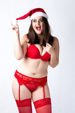 Happy cute fat Santa girl. Model in red lingerie and Santa hat. XXL woman celebrating Christmas and New Year