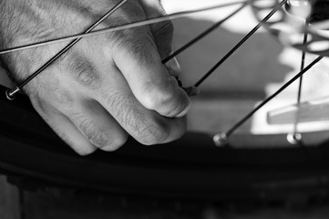 Obraz premium Man is opening the nipple and getting ready for pumping bicycle tyre outdoors, close-up of hands. Black and white filter
