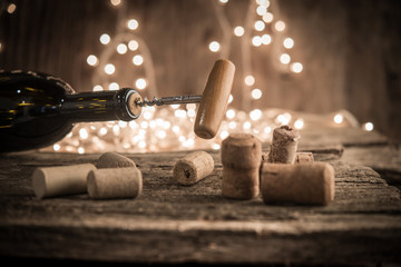 Cork screw and wine bottleOpening a wine bottle with corkscrew on shiny holidey lihgts