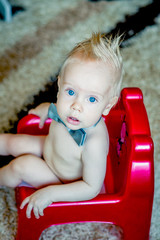 Baby girl sitting on green potty in home interior