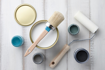 Paint brush, sponge roller, paints, waxes and other painting or decorating supplies on white wooden...