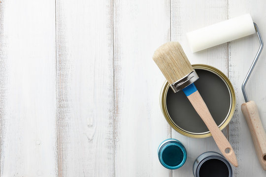 Paint Brush, Sponge Roller, Paints, Waxes And Other Painting Or Decorating Supplies On White Wooden Planks, Top View