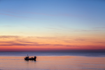 Fototapeta na wymiar Small fisherman boat sailing at dusk