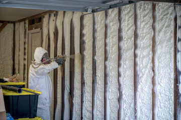 Worker spraying closed cell spray foam insulation on a home that was flooded by Hurricane Harvey