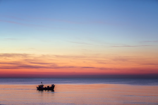 Small fisherman boat sailing at dusk