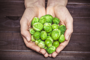 Brussels sprouts in hands, on a dark background.