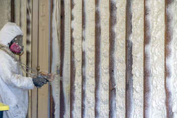 Worker spraying closed cell spray foam insulation on a home that was flooded by Hurricane Harvey