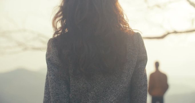 Close-up frame below a woman with long curly hair goes man shining sun in the mountains landscape travel active couple happy girl hiking sun tourist walkin sunset tourism Slow Motion Shot