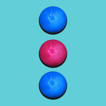 Grapefruit in flat lay Two blue and one pink grapefruits are lying in a row on blue background Top view Modern flat lay photo in pop art style with space for text