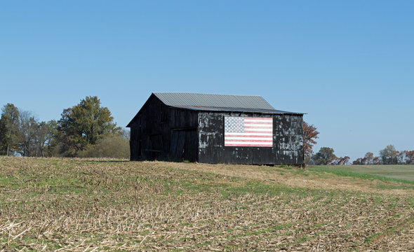 Rural landscape photo of an old barn in a field on a farm with an American flag painted on it