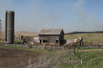 Flint Hills burning off yearly grass behind farm buildings,