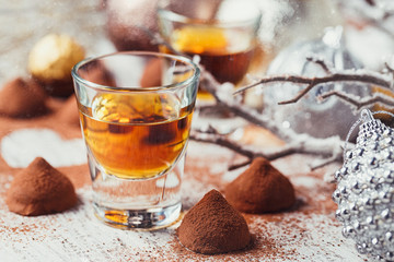 Whiskey or liqueur, truffle chocolate candies in cocoa powder and christmas decorations on white...
