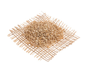 Sesame. Grains over hessian fabric, isolated white background.