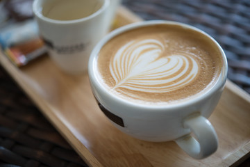 Close up latte art on wooden plate in coffee shop vintage style,selective focus