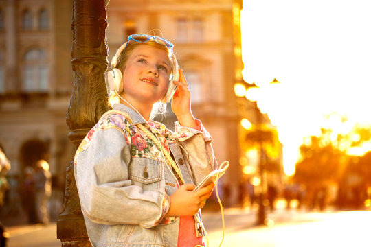 Pretty  young girl listening music with her headphones in the street
