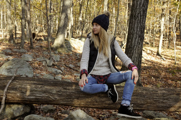 Girl is sitting in autumn forest in the mountains. Hiking and traveling
