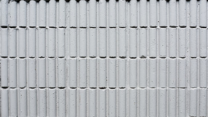 a close-up of a white concrete wall with a repeating pattern of vertical rectangular indentations.