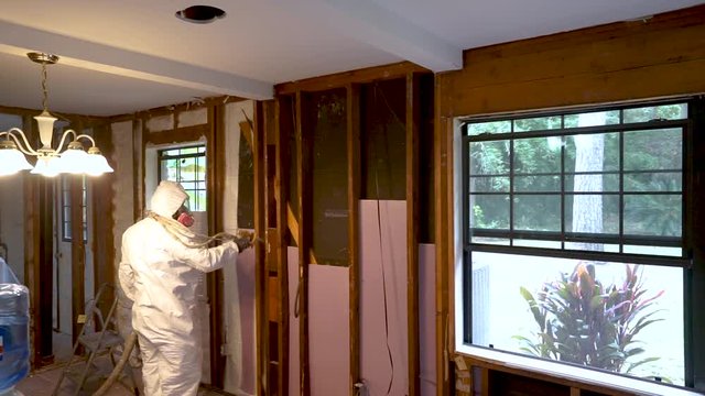 Worker spraying closed cell spray foam insulation on a home that was flooded by Hurricane Harvey