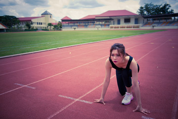 Fototapeta premium Young asian woman in a position start on a running track