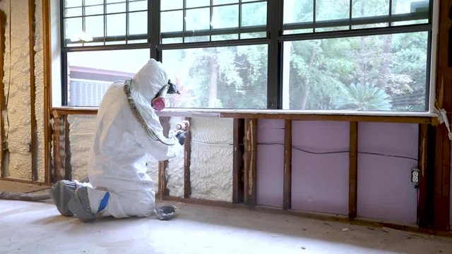Worker spraying closed cell spray foam insulation on a home that was flooded by Hurricane Harvey