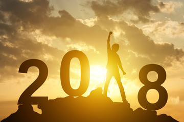 Man hand up on the peak of mountain and sunlight  with text 2018 sign happy new year calendar holiday concept