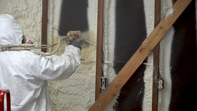 Worker spraying closed cell spray foam insulation on a home that was flooded by Hurricane Harvey